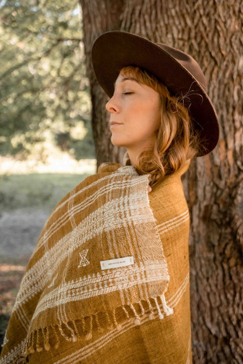 Woman wearing a hat and a traditional golden turmeric woollen shawl